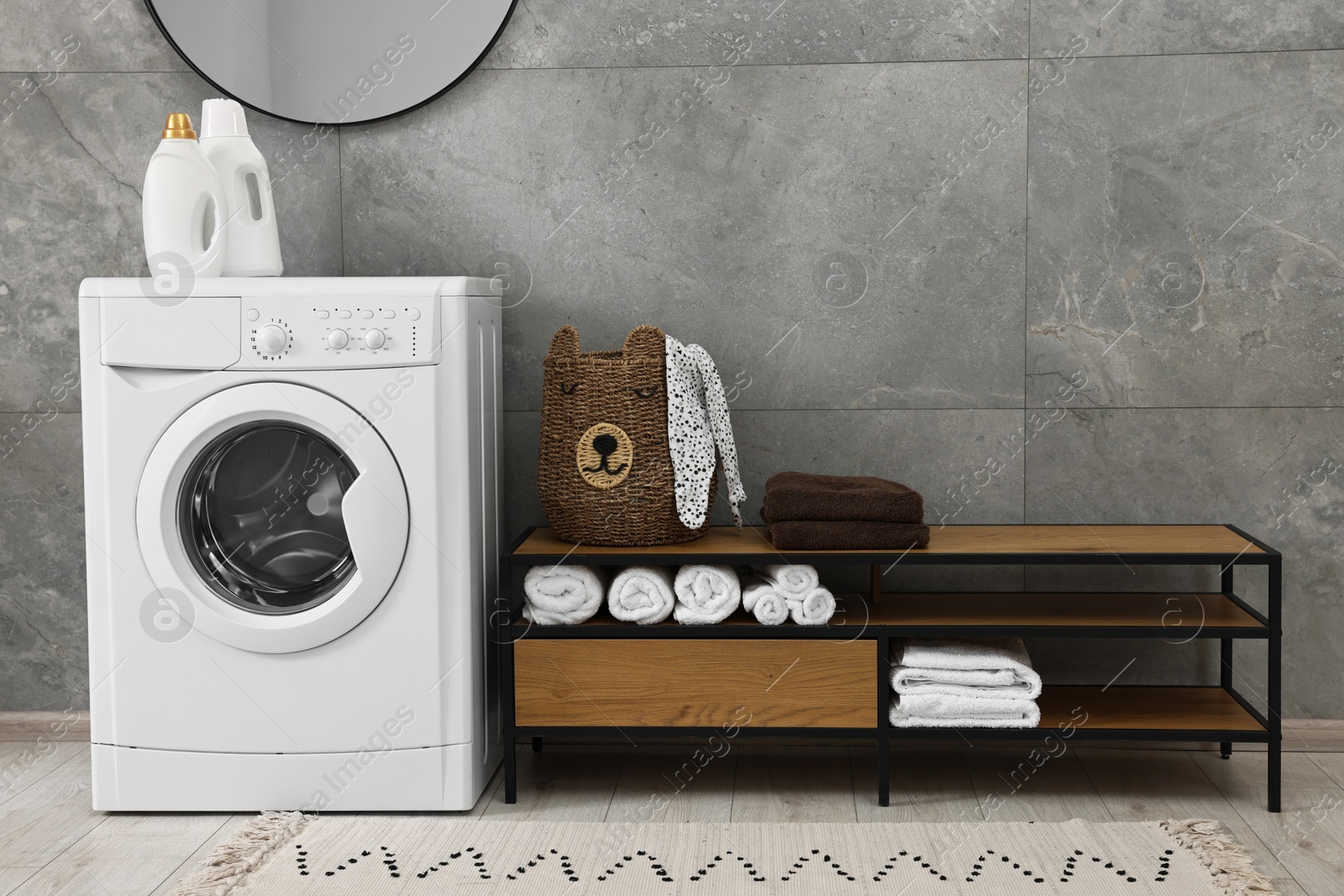 Photo of Washing machine, detergents, towels, basket and storage cabinet in laundry room