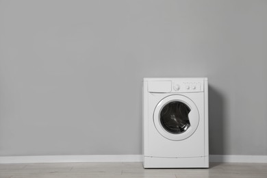 Photo of Washing machine near grey wall indoors, space for text