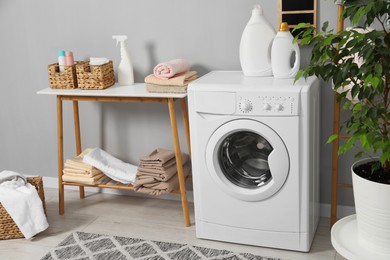 Washing machine, storage bench, detergents, laundry and houseplant indoors