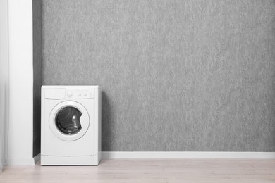 Photo of Washing machine near grey wall indoors, space for text