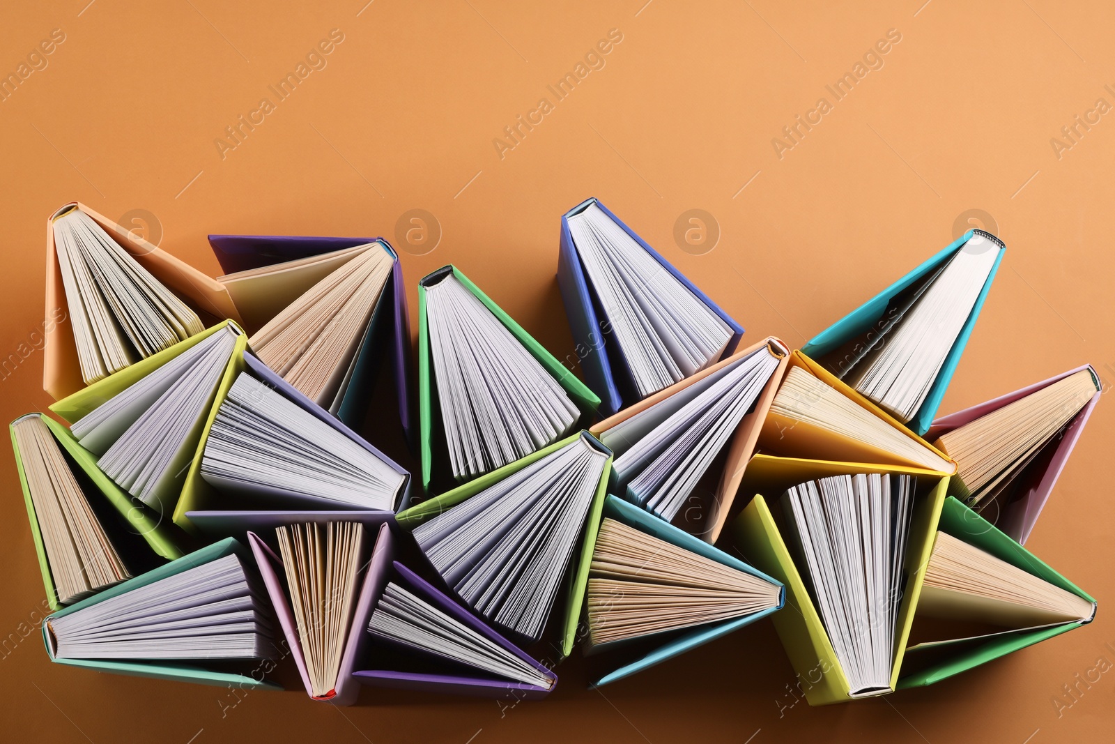 Photo of Many colorful books on orange background, flat lay