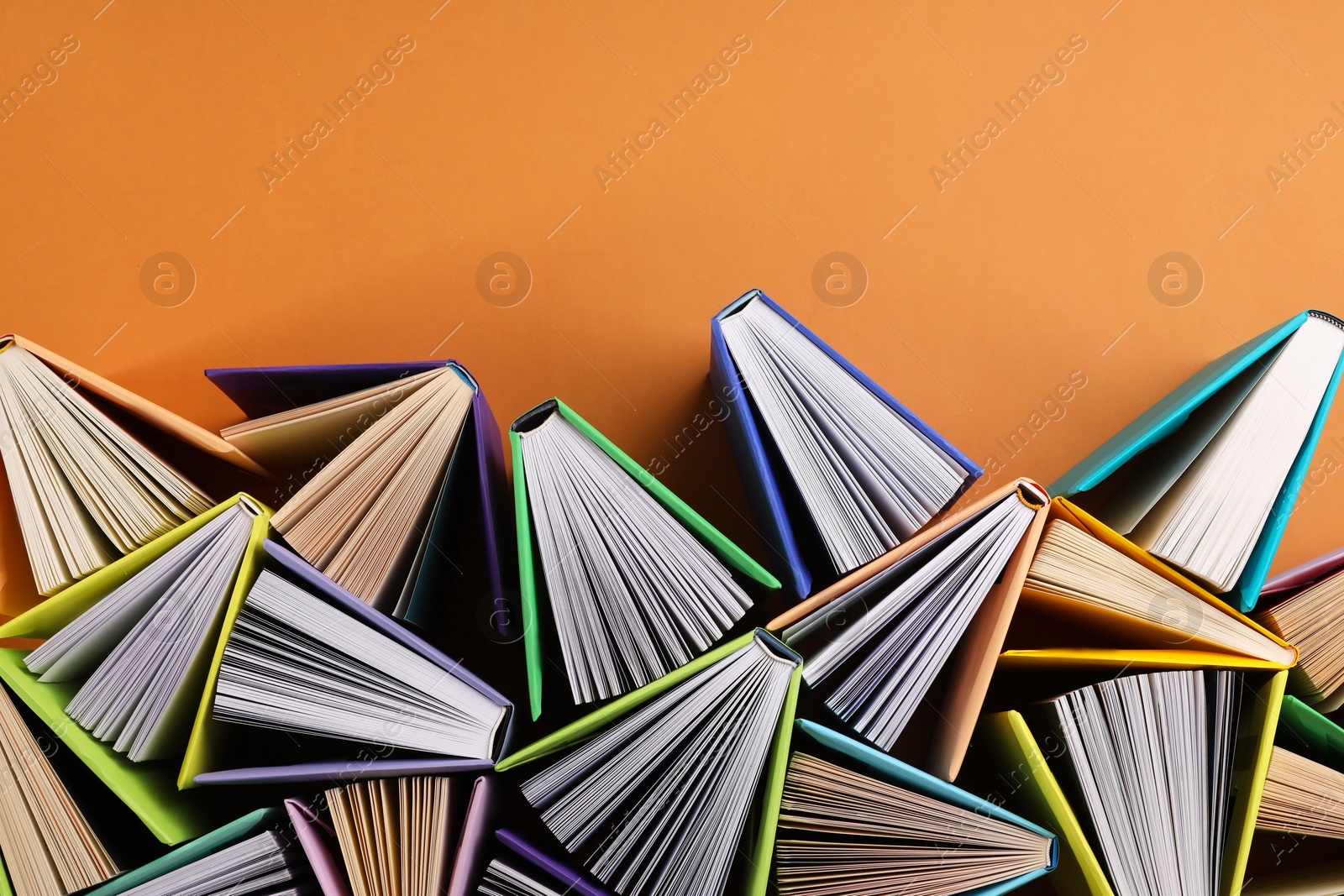 Photo of Many colorful books on orange background, flat lay