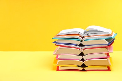 Photo of Stack of colorful books on yellow background, space for text