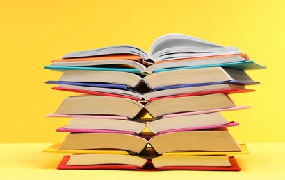 Photo of Stack of colorful books on yellow background