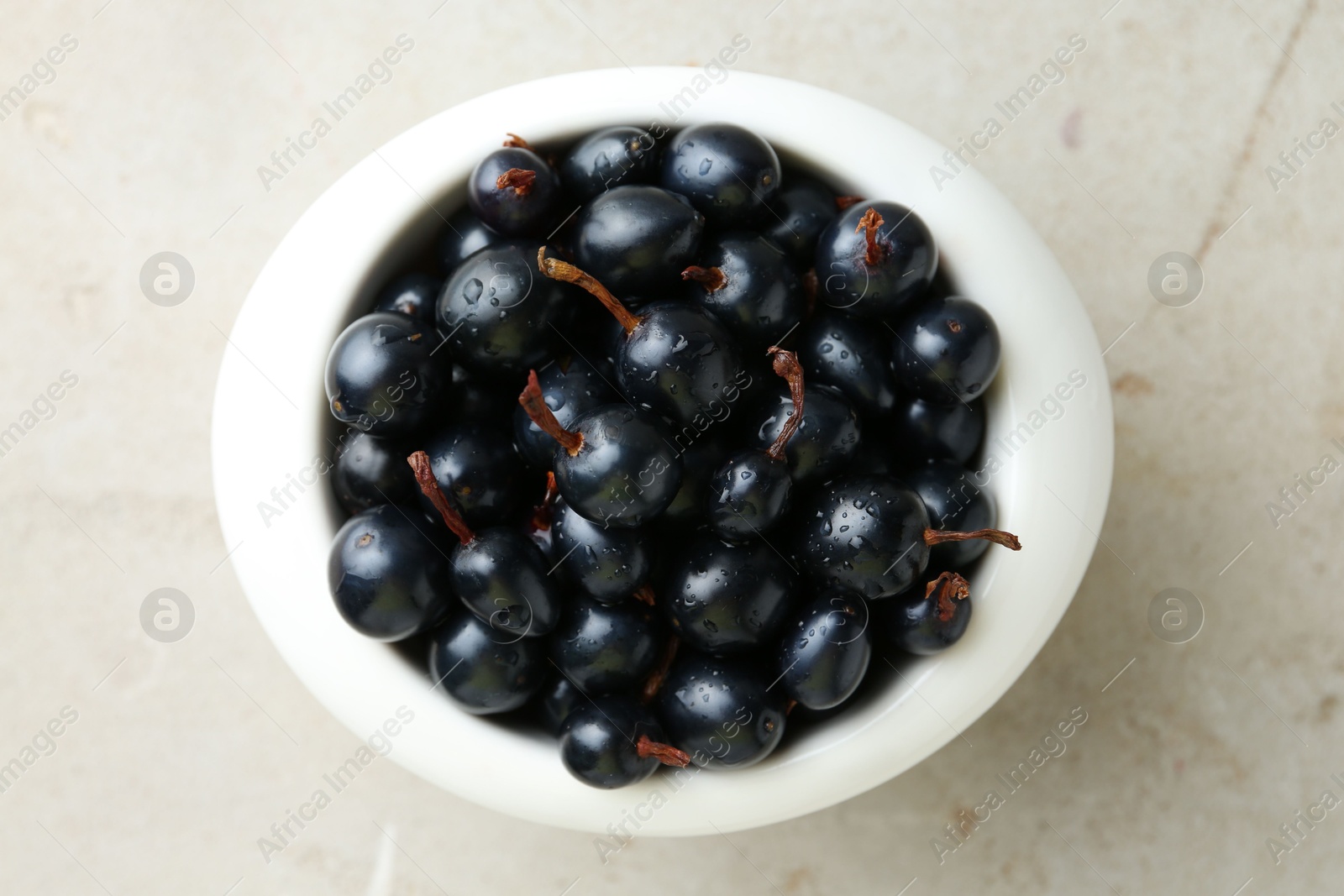 Photo of Ripe black currants in bowl on light table, top view