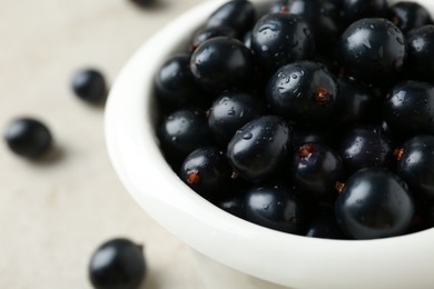 Ripe black currants in bowl on light table, closeup