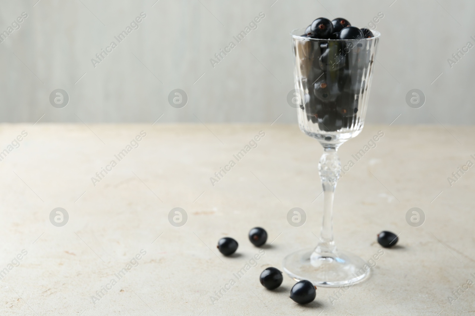 Photo of Fresh ripe black currants in glass on light table. Space for text