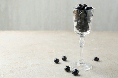 Fresh ripe black currants in glass on light table. Space for text