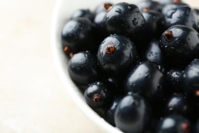 Ripe black currants in bowl on light table, closeup