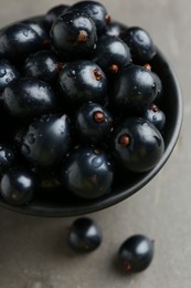 Ripe black currants in bowl on grey table, closeup