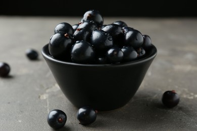 Ripe black currants in bowl on grey table, closeup