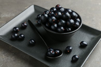 Ripe black currants with water drops on grey table