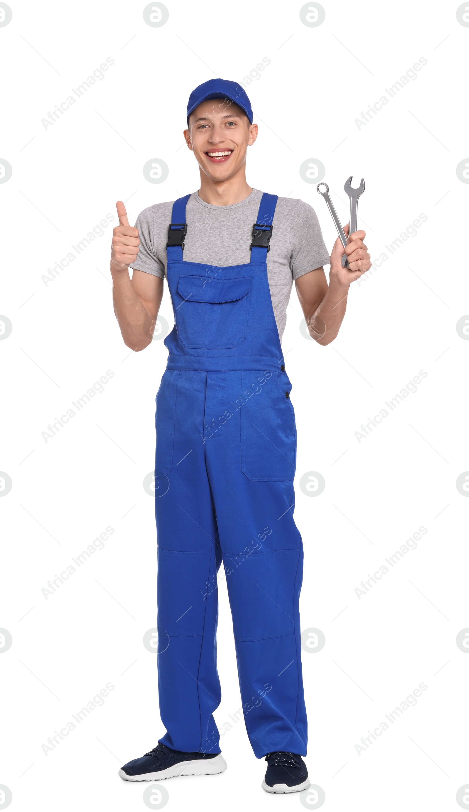 Photo of Smiling auto mechanic with wrenches showing thumb up on white background