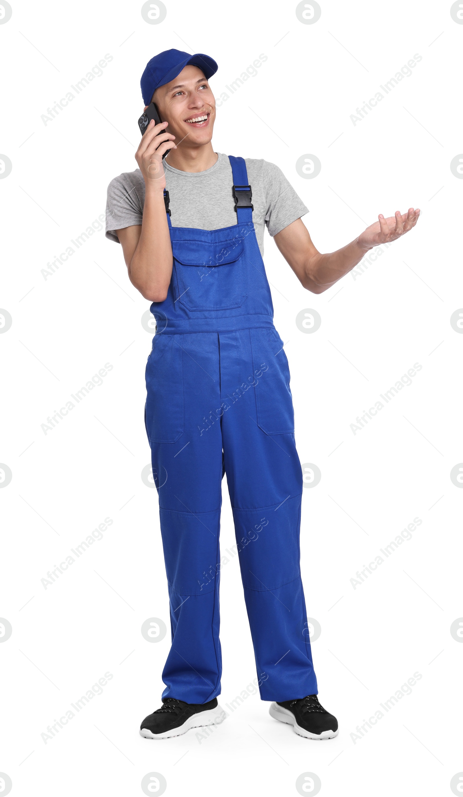 Photo of Smiling auto mechanic talking by smartphone on white background
