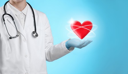 Image of Doctor holding red heart on light blue background, closeup. Banner design