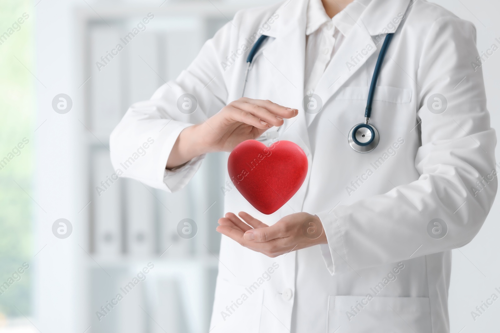 Image of Doctor holding red heart in clinic, closeup