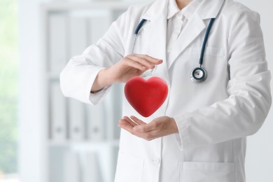 Image of Doctor holding red heart in clinic, closeup