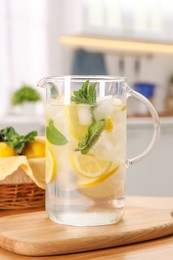 Photo of Freshly made lemonade with mint in jug on wooden table indoors