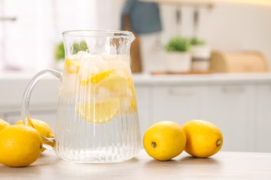 Photo of Freshly made lemonade in jug on white wooden table indoors