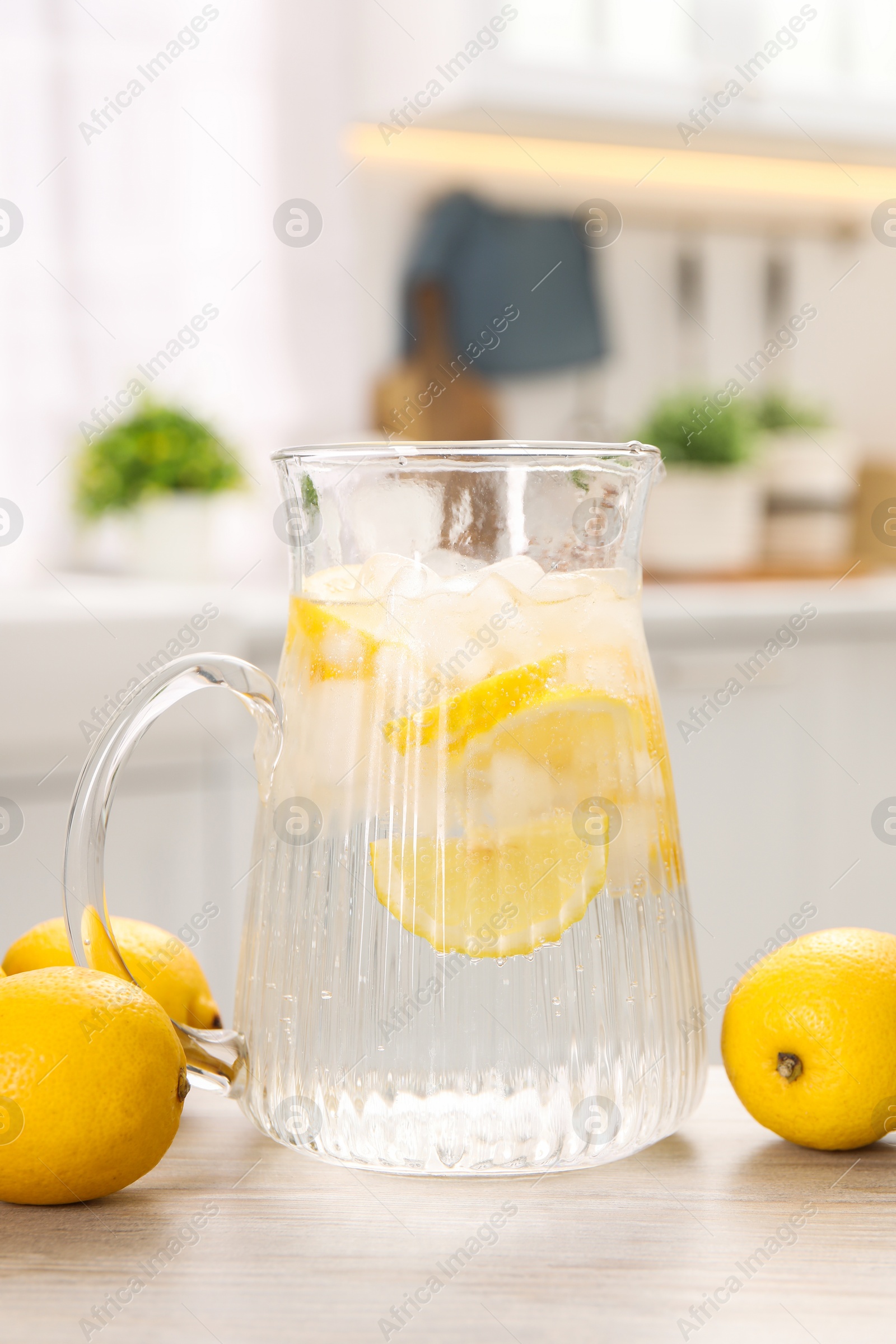 Photo of Freshly made lemonade in jug on white wooden table indoors