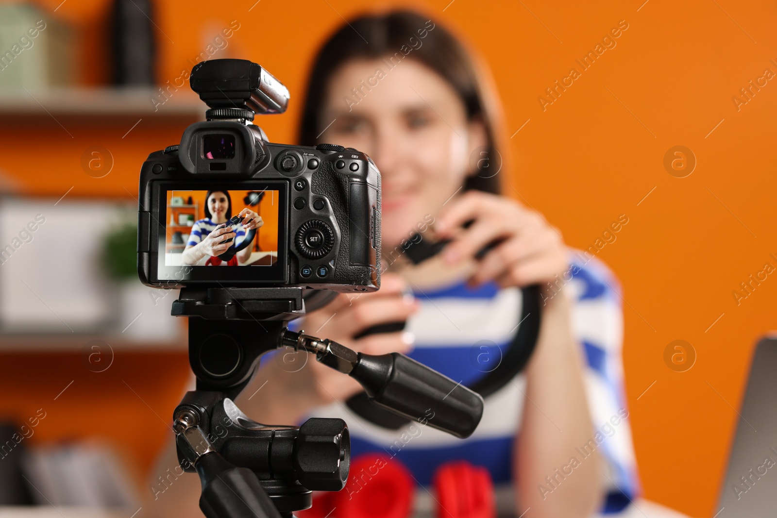 Photo of Technology blogger explaining something while recording video at home, focus on camera