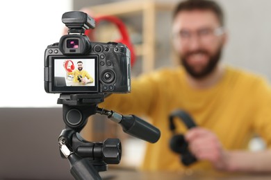 Photo of Technology blogger explaining something while recording video at home, focus on camera