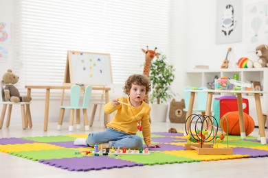 Cute little boy playing with math game Fishing for Numbers on puzzle mat in kindergarten