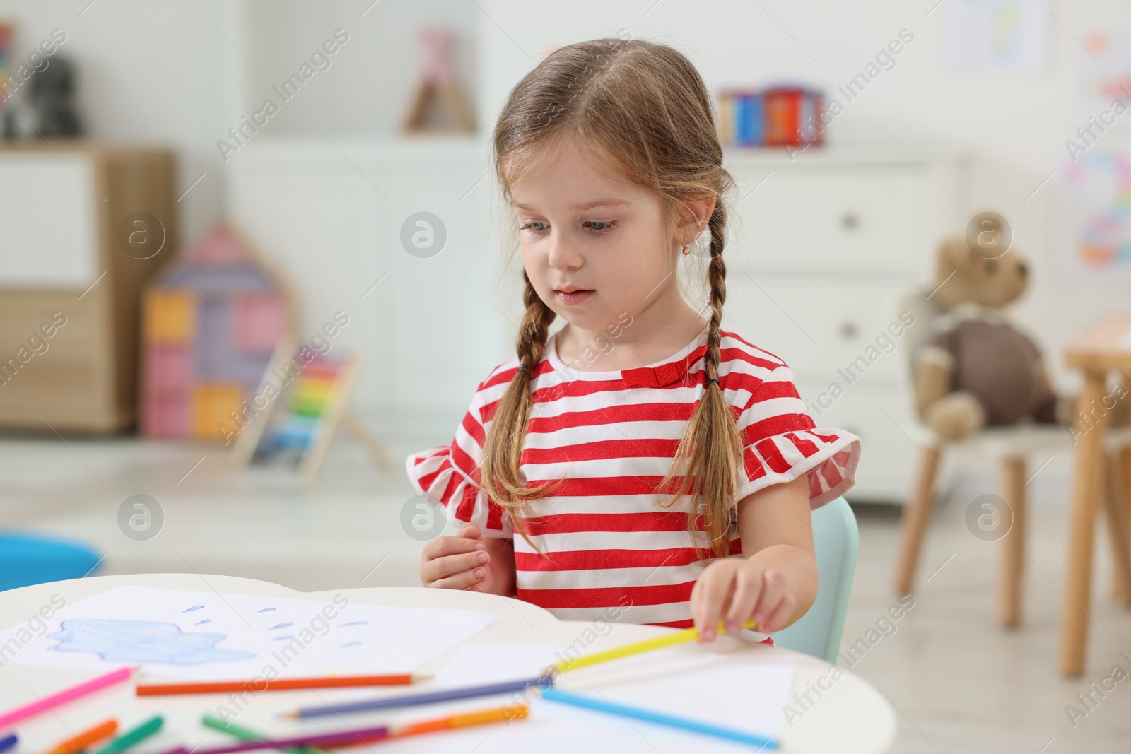 Photo of Cute little girl drawing at white table in kindergarten