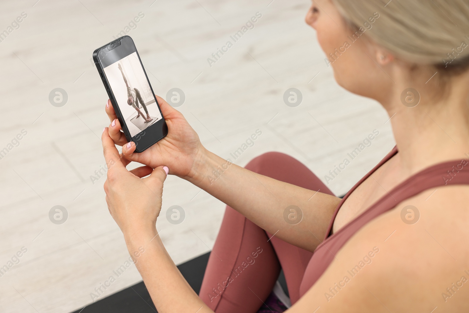 Photo of Online fitness trainer. Woman watching tutorial on smartphone indoors, above view