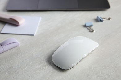 Photo of Wireless mouse and stationery on light wooden table, closeup