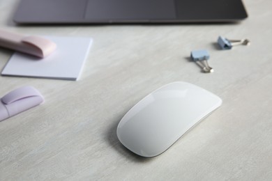 Wireless mouse and stationery on light wooden table, closeup