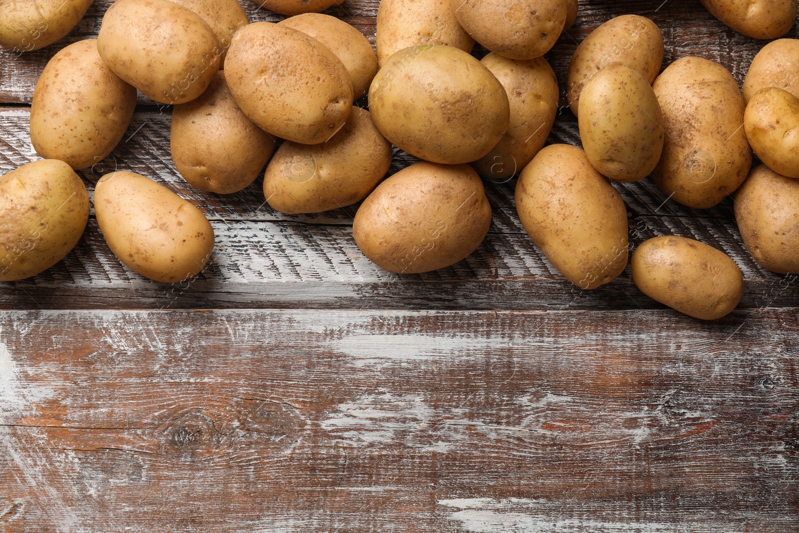 Photo of Many fresh potatoes on wooden rustic table, top view. Space for text