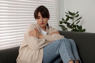 Photo of Loneliness concept. Sad woman sitting on sofa at home