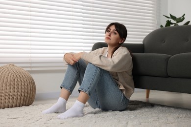 Photo of Loneliness concept. Sad woman sitting on floor at home