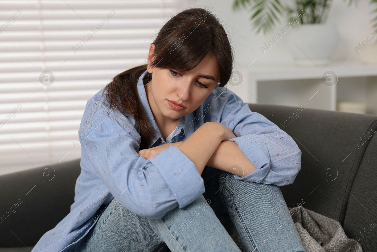 Photo of Loneliness concept. Sad woman sitting on sofa at home