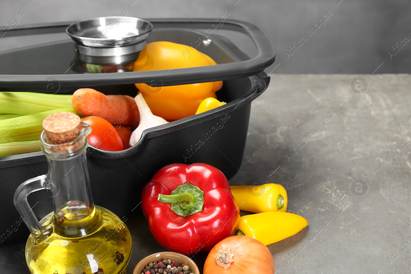 Photo of Black pot and fresh products on grey table, space for text