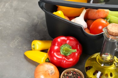 Photo of Black pot and fresh products on grey table, space for text