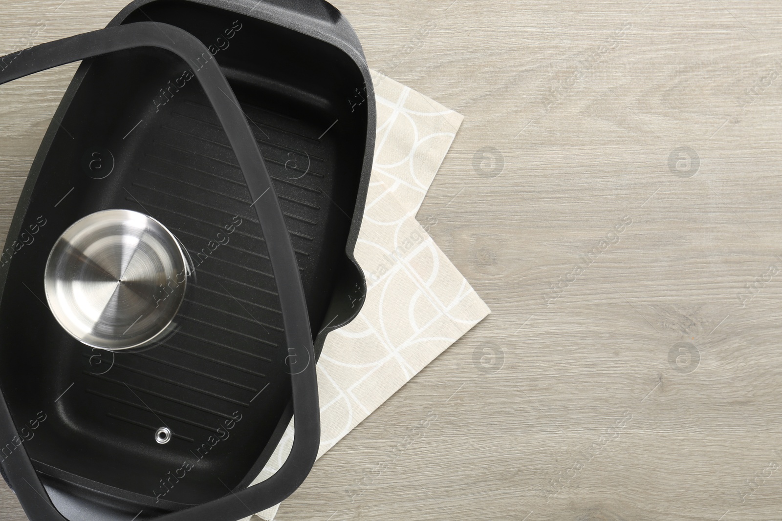 Photo of Black pot with glass lid on wooden table, top view. Space for text