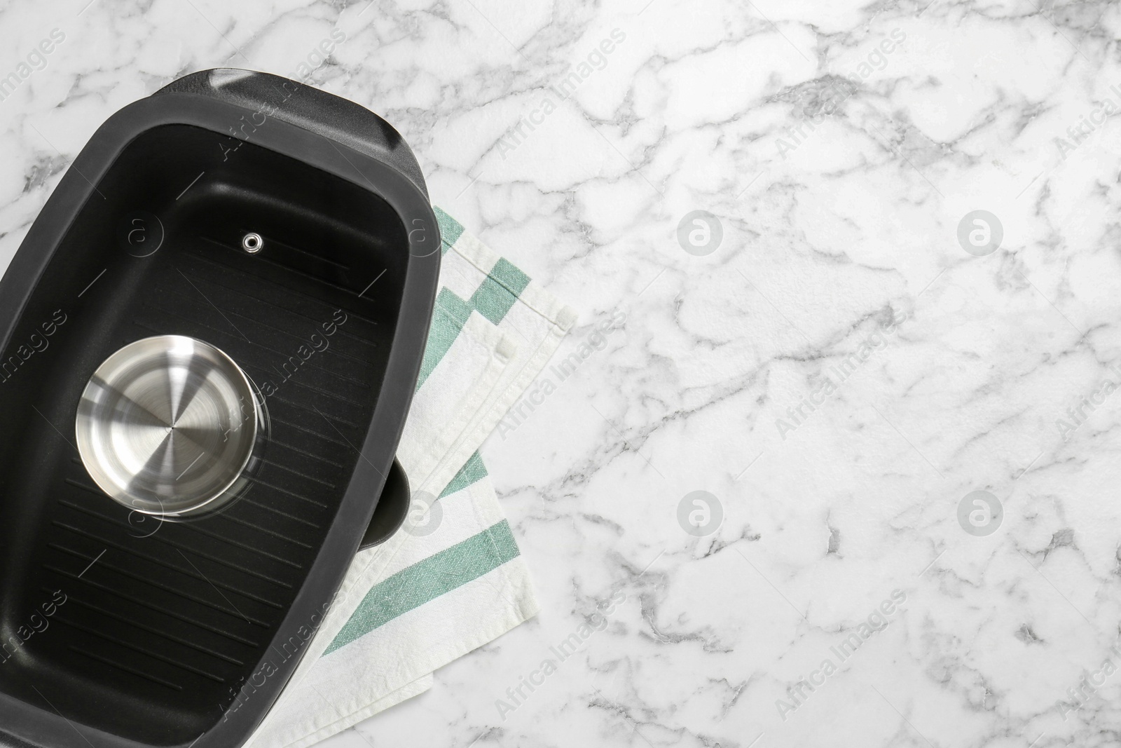 Photo of Black pot with glass lid on white marble table, top view. Space for text