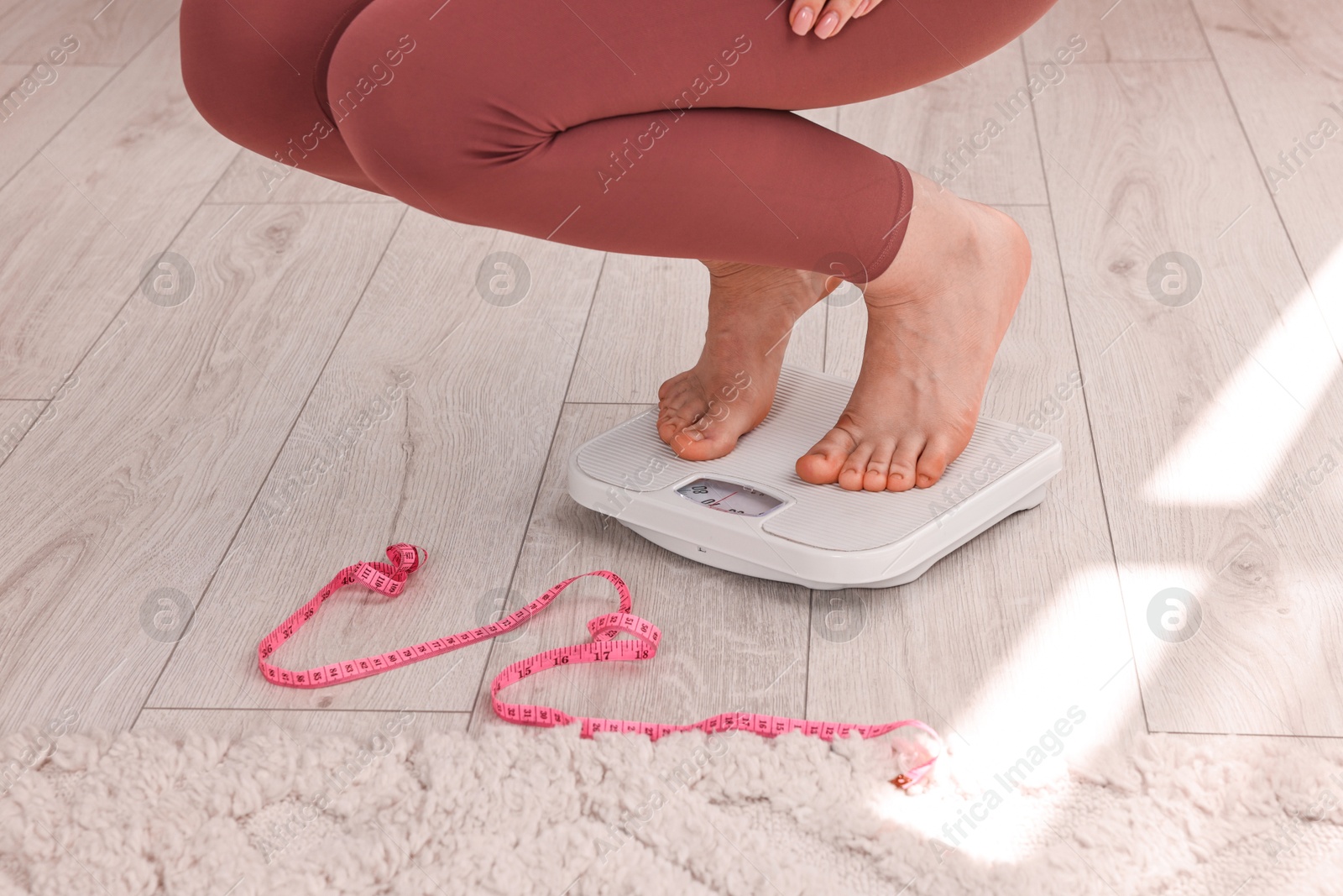 Photo of Woman on floor scale and measuring tape at home, closeup. Weight control