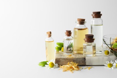 Photo of Aromatherapy. Different essential oils, dry flowers, chamomiles and fir twigs on white background, space for text