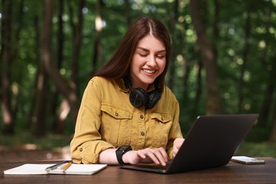 Smiling freelancer working with laptop at table outdoors. Remote job