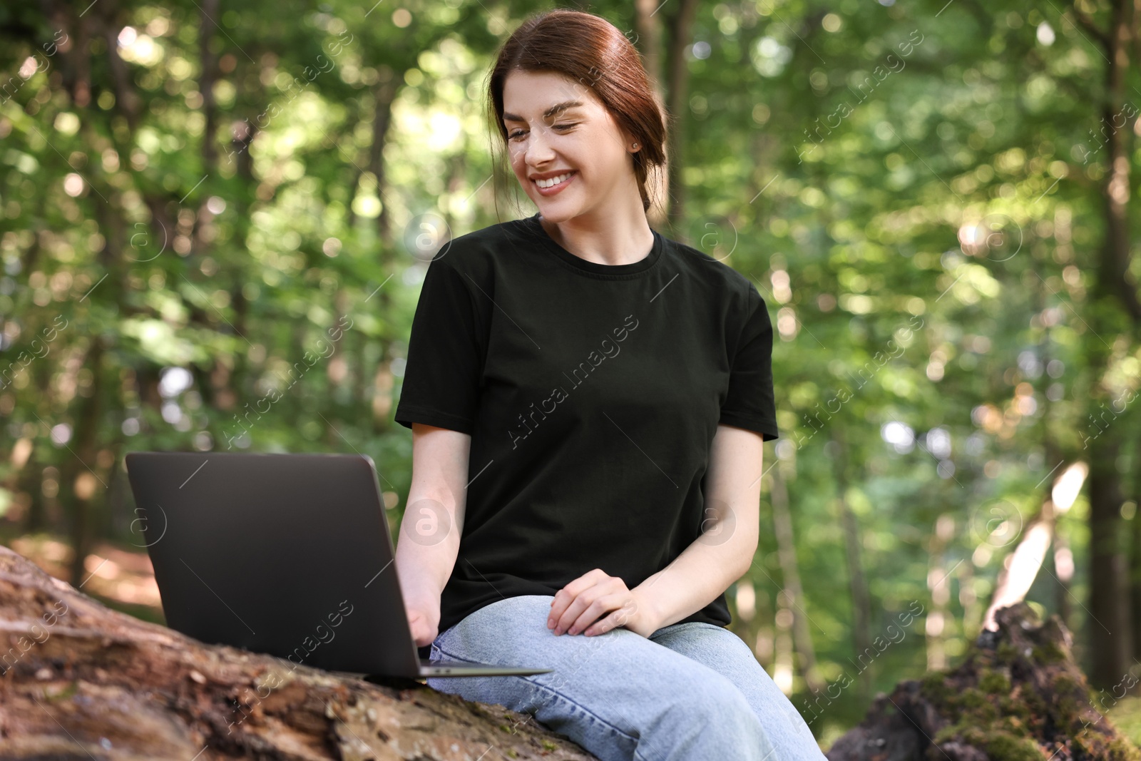 Photo of Smiling freelancer working with laptop in forest, low angle view. Remote job