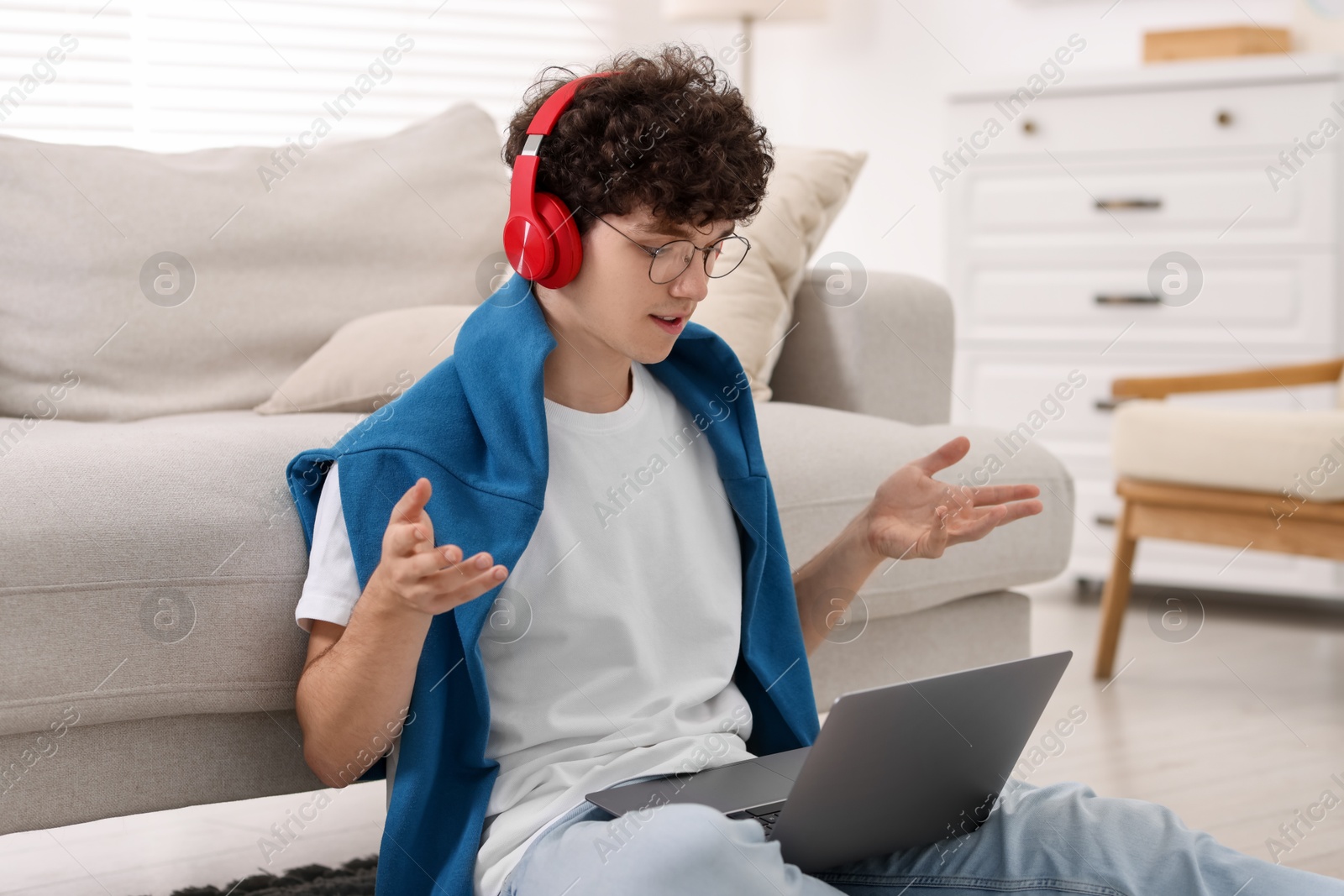 Photo of Teenager in headphones having video chat via laptop at home. Remote work