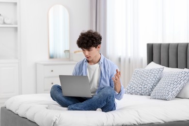 Teenager having video chat via laptop on bed at home. Remote work