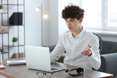 Photo of Teenager having video chat via laptop at table indoors. Remote work