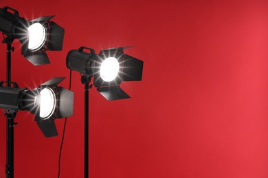 Red photo background and professional lighting equipment in studio, space for text