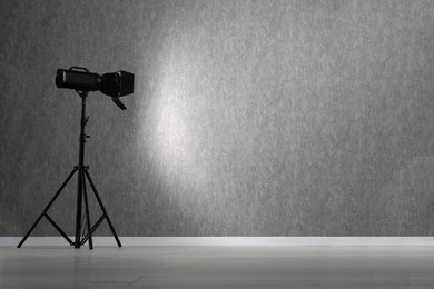 Grey photo background and professional lighting equipment in studio, space for text