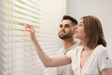 Young couple near window blinds at home