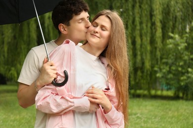 International dating. Lovely young couple with umbrella spending time together in park